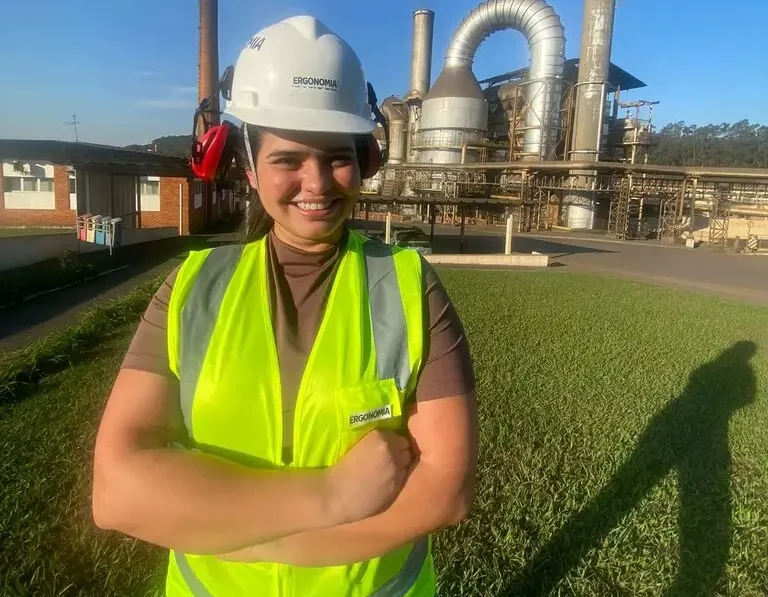 Camila em frente à fábrica Ergonomia